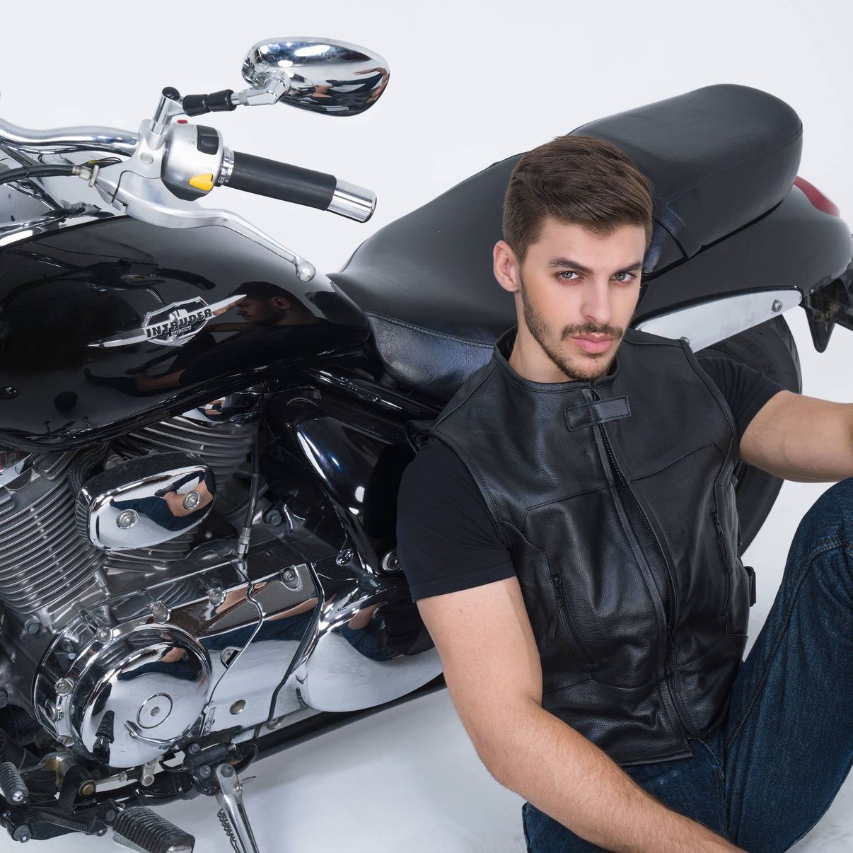 A model wears a black full-grain leather motorcycle vest with zipper pockets and straps
