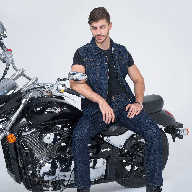 Man sitting on a motorcycle wearing a denim outfit against a white background