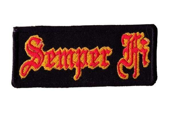 A close-up of a black embroidered biker patch featuring red and yellow stitching