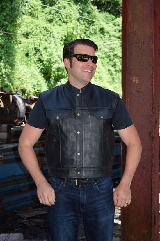 A model wears a black cowhide leather motorcycle vest featuring front pockets and snap closures
